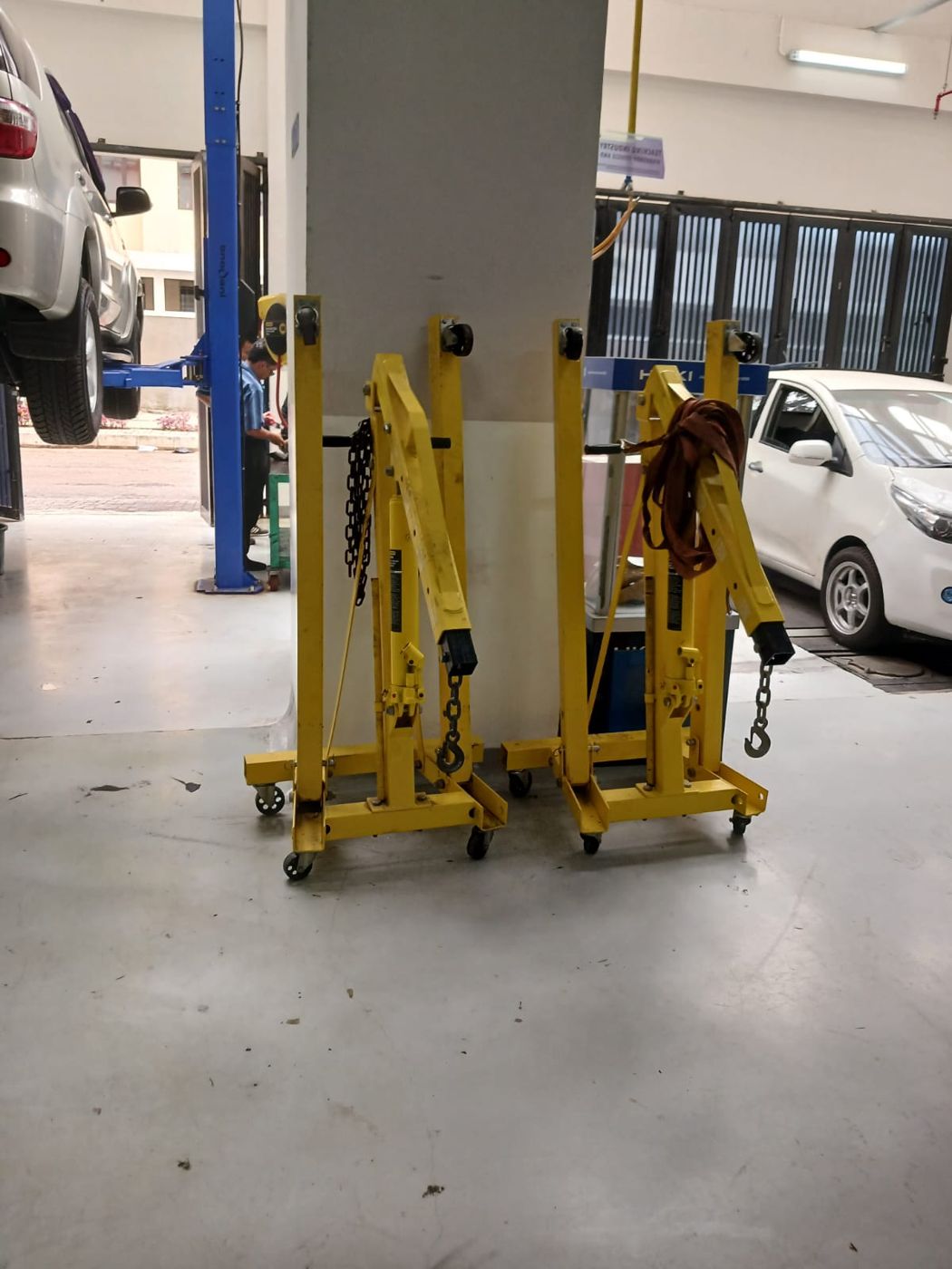 Two engine cranes next to a two-post vehicle lift